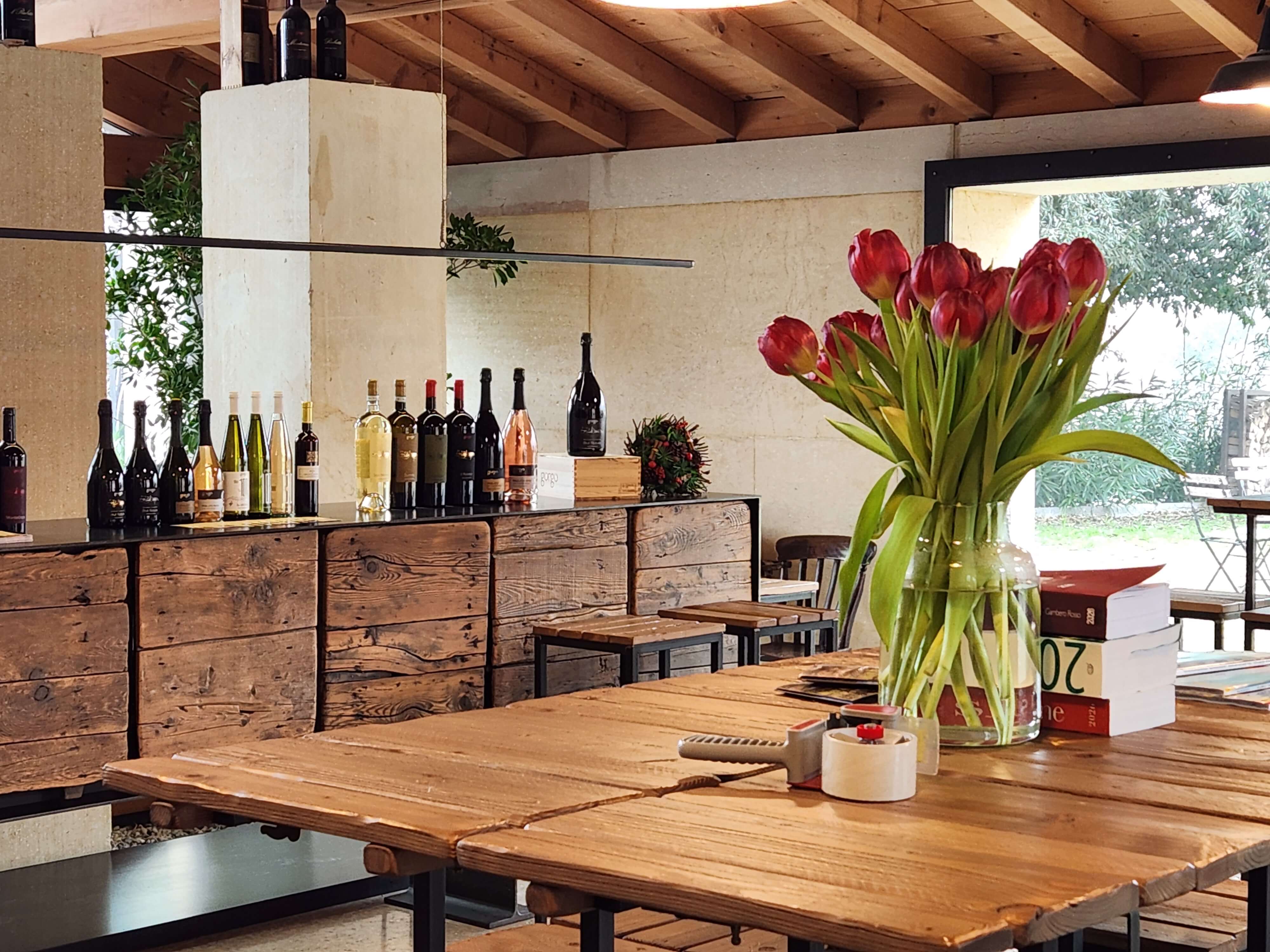 Salle de dégustation d'un domaine en Lugana, bouteilles alignées et tulipes rouges, lac de Garde