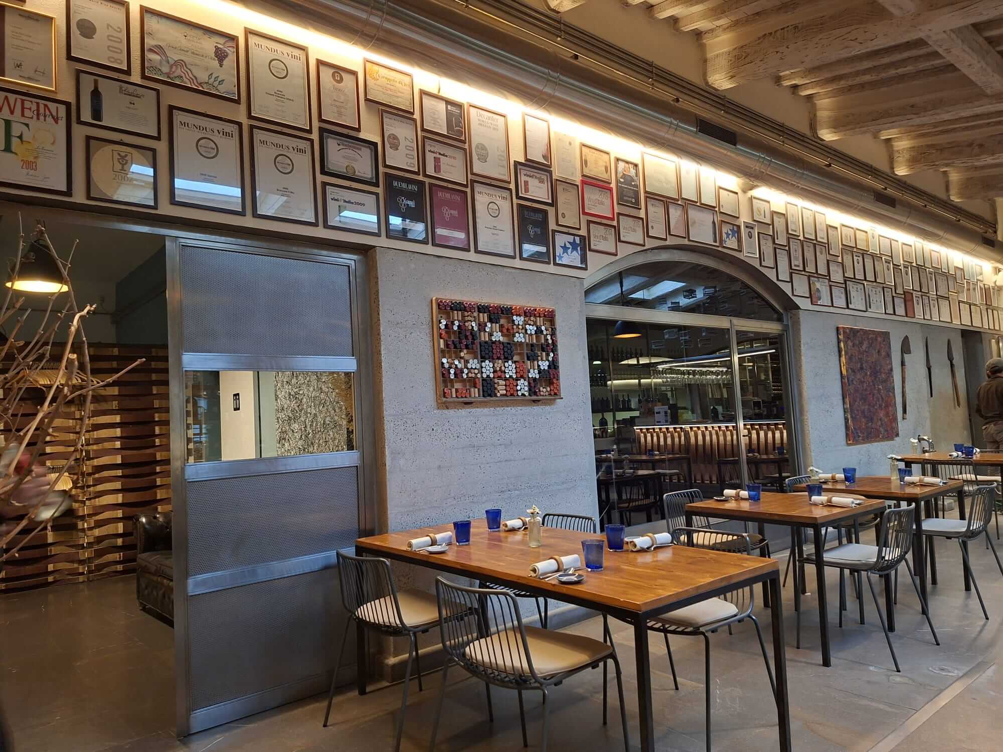 La salle du restaurant de le domaine avec ses diplômes au mur et ses tables en bois