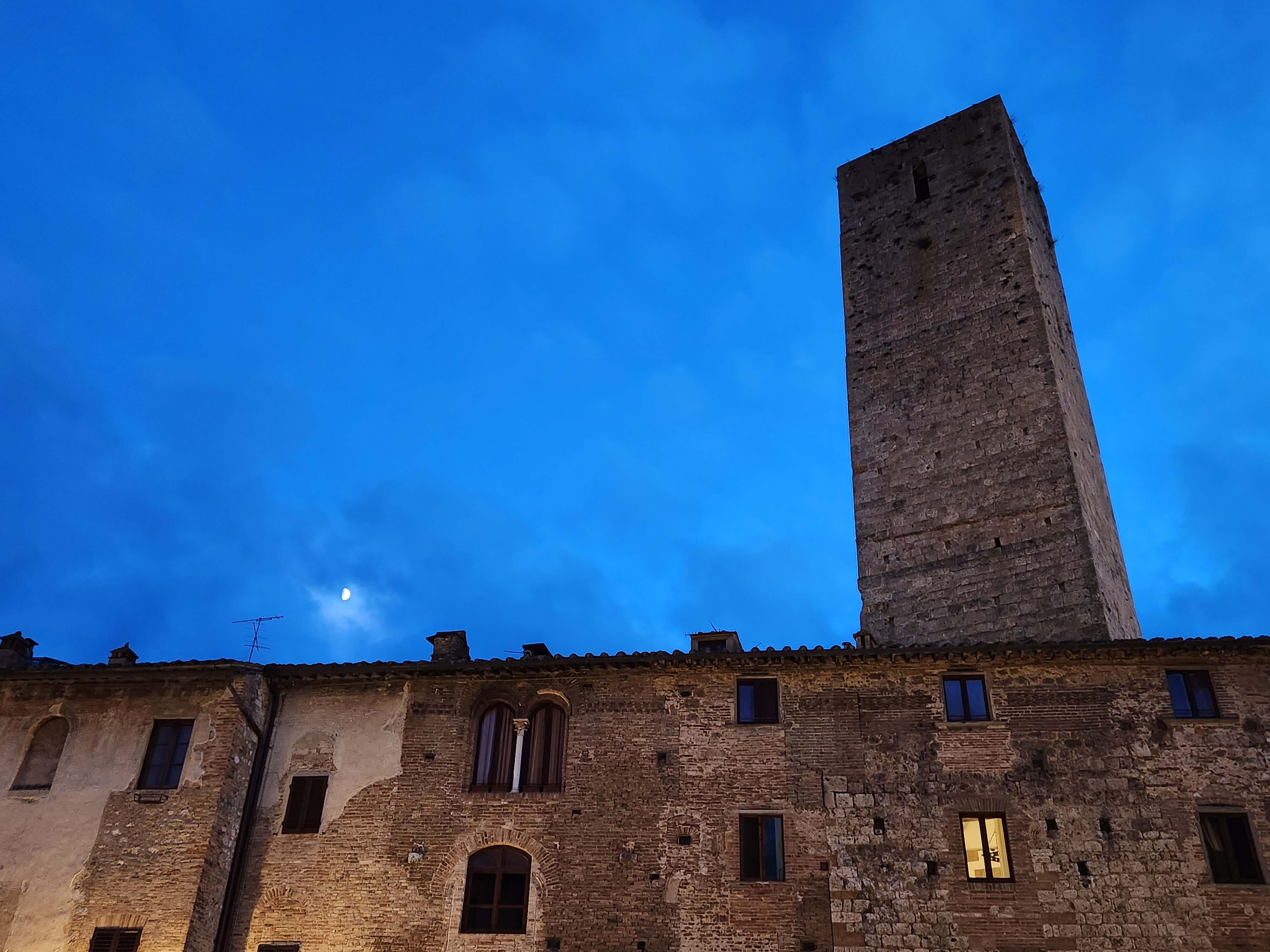 Tour médiévale de San Gimignano contre un ciel bleu nuit avec la lune