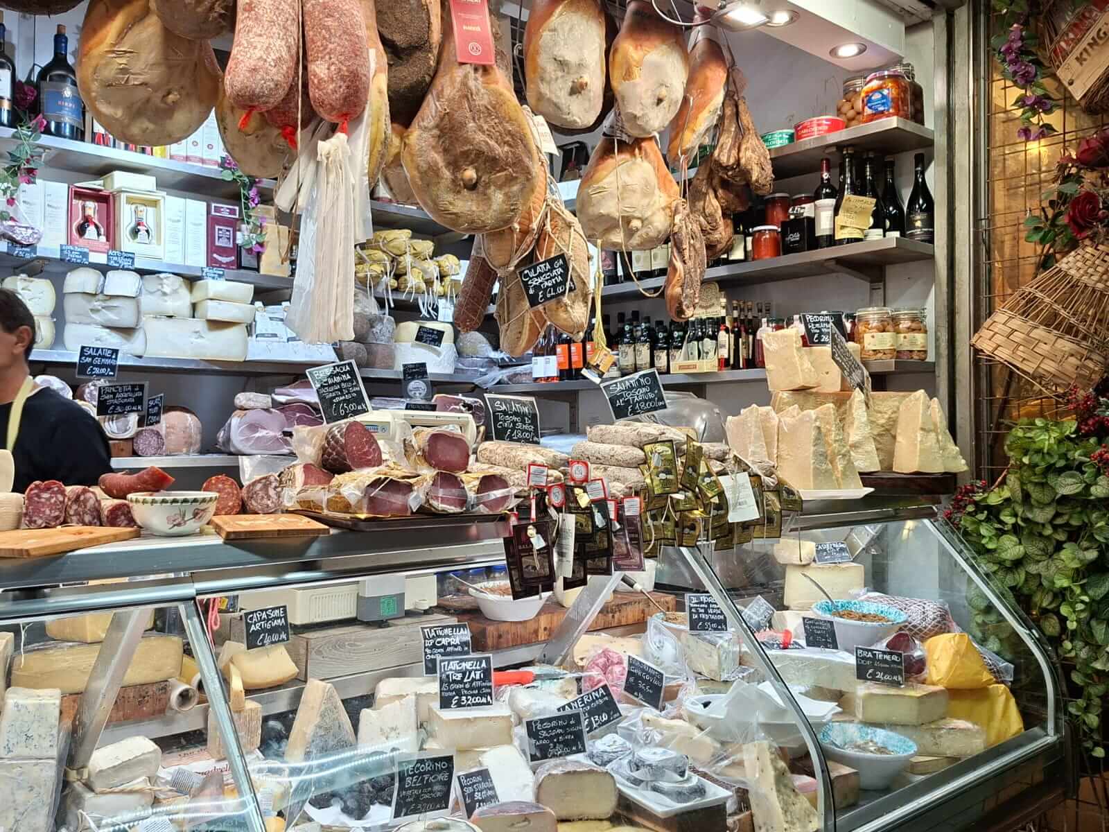 Étal de charcuterie et fromages du marché de Florence, jambons suspendus au plafond